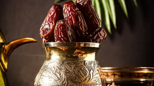 An engraved golden container full of dates.