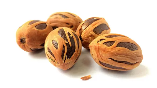 Nutmeg seeds sitting against a white background.