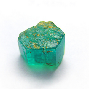 A brilliant semi-clear emerald chunk lightly covered in golden inclusions, well lit atop a white surface to better see impurities and inclusions. Dennis Harper Emerald03 olym 600ct 4251ap (CC BY-ND 2.0) | Emerald Metaphysical Properties and Meaning |