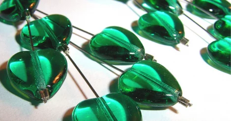 An up close picture of Emerald Heart earrings, each earring holding several small, clear emerald hearts on wires. Well lit, resting atop a white surface to showcase the clarity of the emeralds. Nikita Kashner Emerald Hearts Closeup (CC BY-NC-ND 2.0) | Emerald Metaphysical Properties and Meaning |