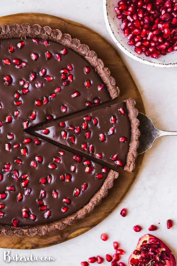 A vegan chocolate tart embedded with pomegranate seeds.