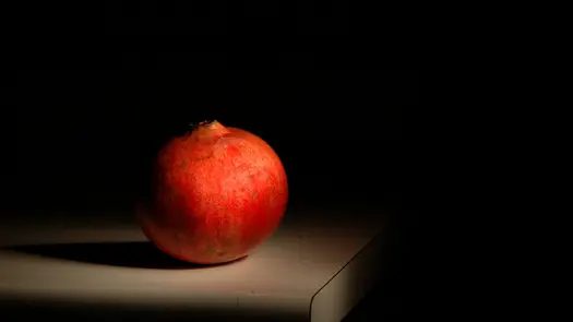 A pomegranate on a table in a dimly lit room.