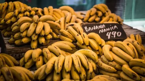 Bunches of bananas on sale with a black sign nearby that says "Banana Nanica 4.90."
