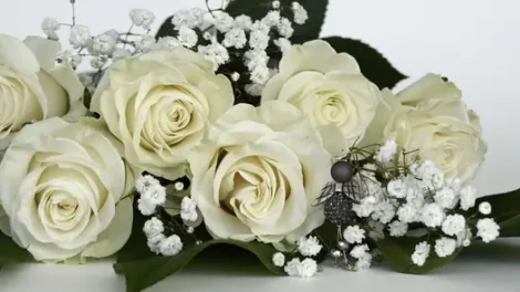 A white rose and white baby's breath bouquet with decorative silver accents.