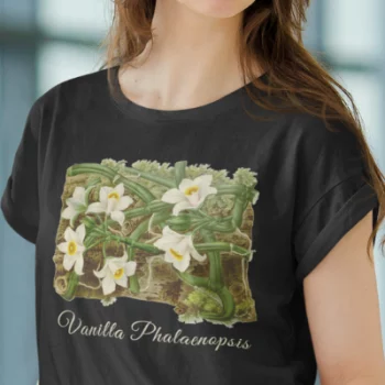 A woman wearing a black t-shirt with a vanilla orchid graphic. Text on the bottom of the vanilla orchid graphic says: "Vanilla Phalaenopsis."