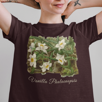 A woman wearing an oxblood black gray t-shirt with a vanilla orchid graphic. Text on the bottom of the vanilla orchid graphic says: "Vanilla Phalaenopsis."