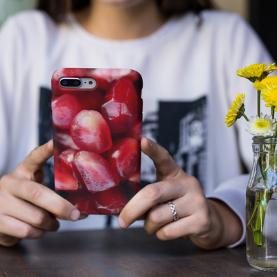 A woman holding an iPhone 8 Plus with a pomegranate iPhone cover from Elune Blue on Etsy.
