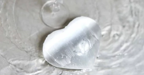 A Selenite Harmonious Heart from Conscious Items, sitting in a stream of water.