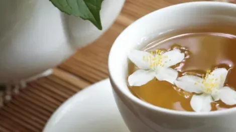 Jasmine petals floating in a white teacup full of jasmine tea.