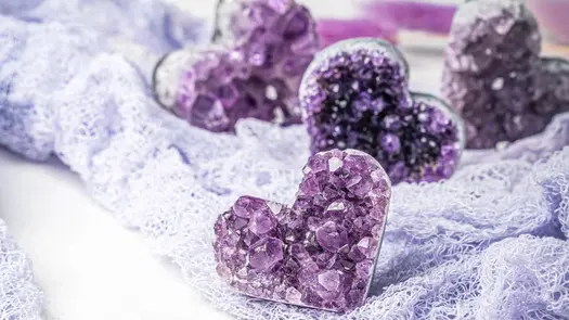 Amethyst heart clusters from Conscious Items sitting on a lavender-colored mesh cloth.