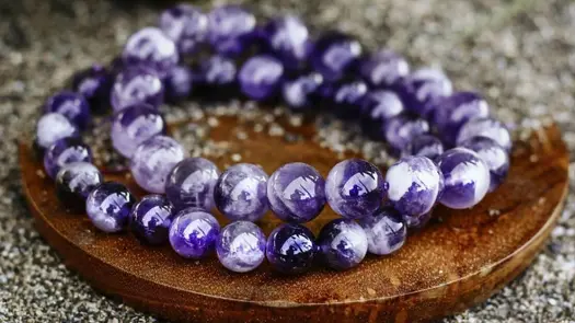 Two purple amethyst bracelets from Conscious Items on a wooden slab.