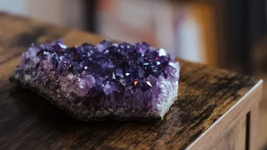 Amethyst cluster sitting on a wooden counter.