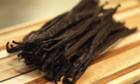 A bundle of vanilla beans on a wooden surface.