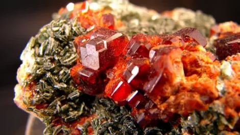 A vibrant red grossular garnet crystal within a matrix,