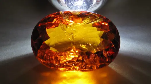 An orange spessartine garnet stone lit from behind by a close light.