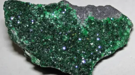 Sparkling green uvarovite crystals on a chromite specimen.