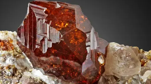 Close-up of a red orange natural andradite garnet crystal.