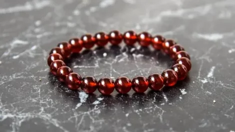 A beaded garnet bracelet from Conscious Items on a marble surface.