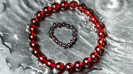 Garnet Universal Love Bracelet and Ring Set from Conscious Items resting in water.