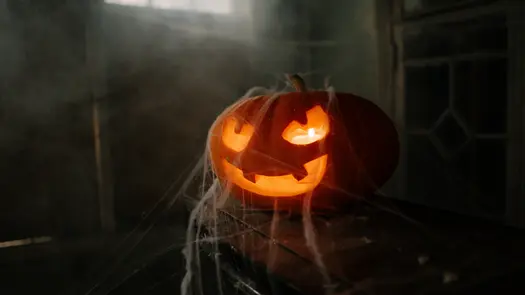 A jack o' lantern draped in faux spiderwebs.
