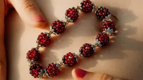 A Natural Garnet Healing Bracelet from Conscious Items resting on a woman's lower abdomen.
