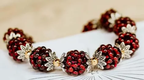 A bracelet with red garnet seed clusters sitting on a drawing of a shining star.