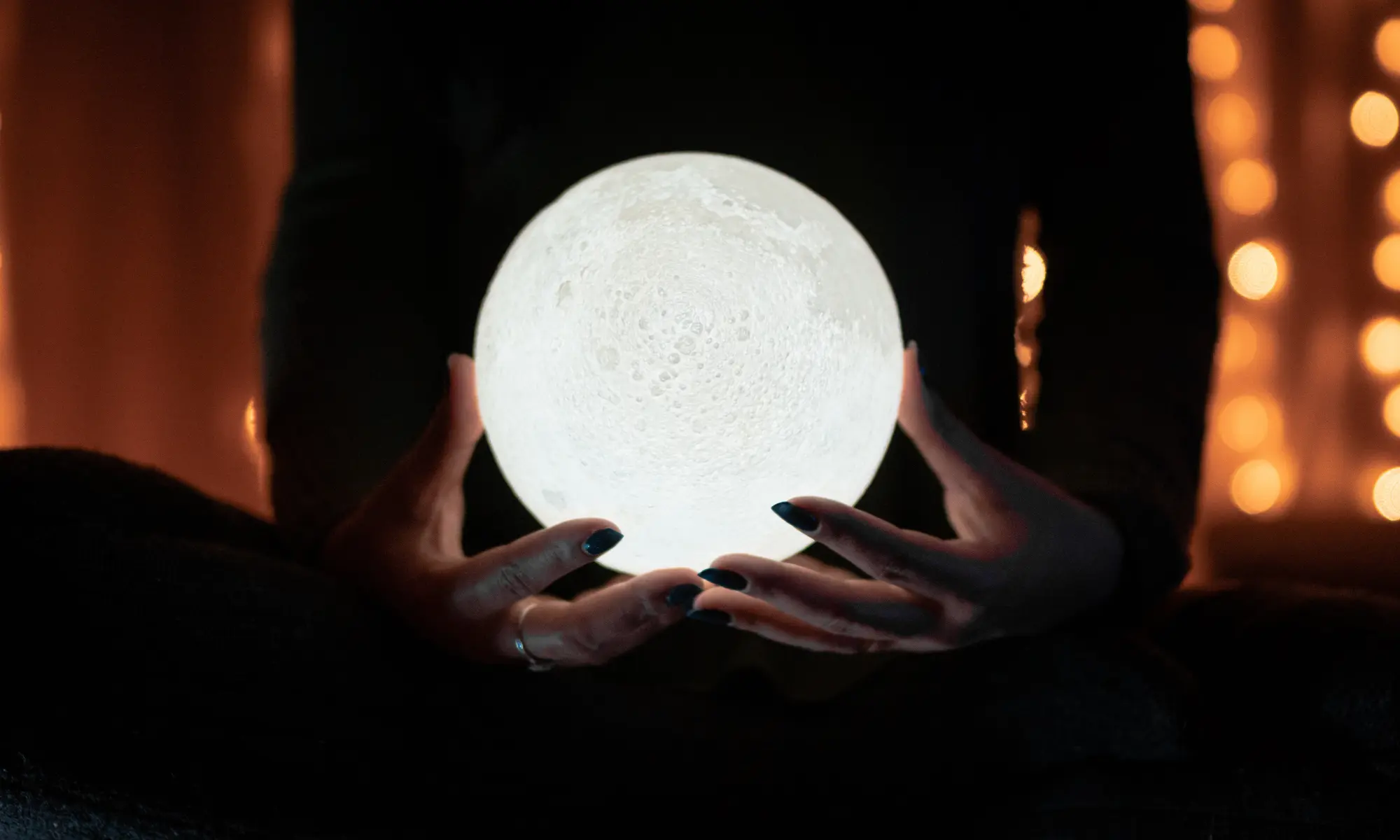 A person holding a glowing, moon-like orb.