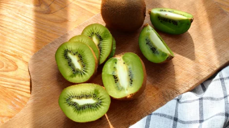 A kiwi fruit on a wooden cutting board.