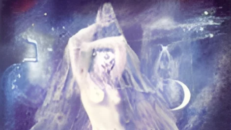The High Priestess from the Celestial Tarot with a veil draped over her head, standing with her hands extended towards the sky.